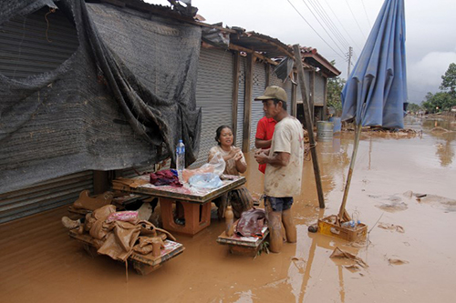 Một gia đình ngồi trên ngôi nhà ngập bùn sau khi lũ rút ở  huyện Sanamxay, tỉnh Attapeu, hôm nay. Ảnh: AFP