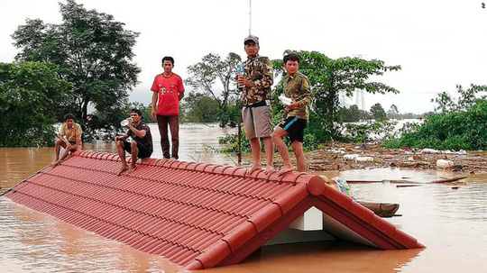 Nhiều nạn nhân phải leo lên mái nhà để tránh nước lũ. Ảnh: CNN