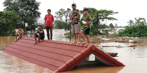 Người dân đứng trên nóc nhà chờ giải cứu khi nước lũ dâng cao do vỡ đập. Ảnh: Attapeu Today